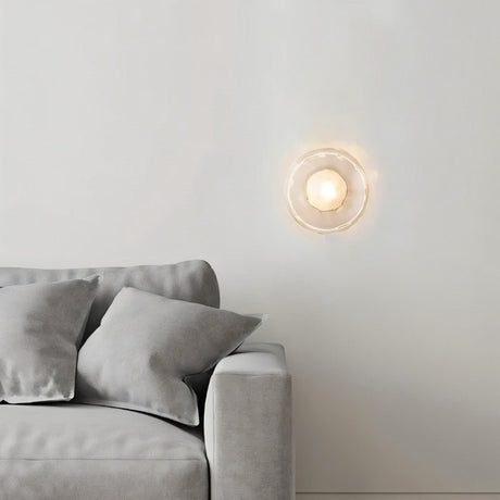 "Modern wall lamp with a clear glass shade illuminating a contemporary living room."