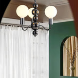 "Walfi chandelier with iron frame and frosted glass globes hanging in an entryway with curtains and a vase."
