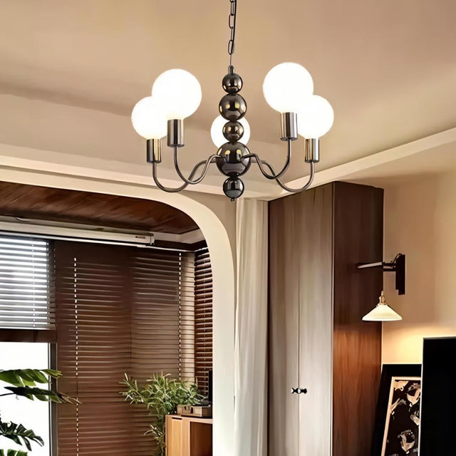 "Walfi chandelier with iron frame and frosted glass globes hanging in a living room with blinds and plants."