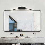 "A modern, curved LED wall lamp illuminating a bathroom mirror over a double sink vanity."