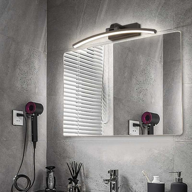 "A modern, curved LED wall lamp illuminating a bathroom mirror with a sink and countertop."