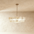 Olive green glass disc chandelier with bronze frame, suspended in bright interior near window with plants below.