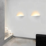 "Two Wiane trimless wall lights illuminating a modern hallway with stairs."