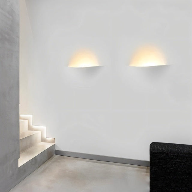 "Two Wiane trimless wall lights illuminating a modern hallway with stairs."