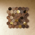 Hexagonal wood and brass tiles in mixed brown tones arranged on studio background, angled perspective view.