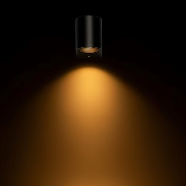 "Modern outdoor wall lamp with a dark aluminum body and glass diffuser, casting a warm, focused beam of light in a dark setting."