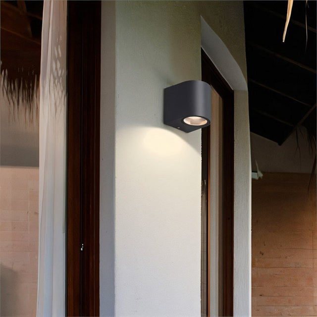 "Modern outdoor wall lamp with a dark aluminum body and glass diffuser, providing focused illumination on a wall."