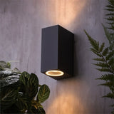 "A modern outdoor wall lamp illuminating a garden wall with a soft, focused light."
