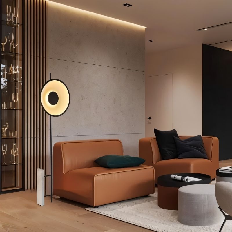 "A halo floor lamp with a sculptural design, illuminating a living room with tan leather armless chairs and modern decor."