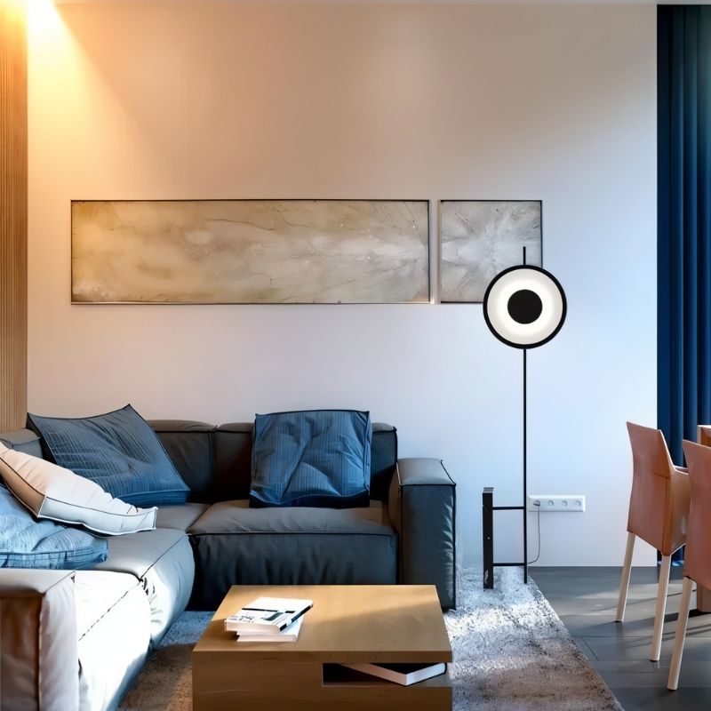 "A modern floor lamp with a circular, halo-like LED design, illuminating a contemporary living room with a diffused glow."