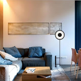 "A modern floor lamp with a circular, halo-like LED design, illuminating a contemporary living room with a diffused glow."