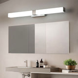 "A silver wall lamp with a linear LED bar illuminating a modern bathroom with grey cabinets, a divided mirror, and a potted plant."