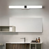 "A silver wall lamp with a linear LED bar mounted above a modern bathroom vanity with a white mirror, dark wood cabinets, and toiletries."