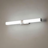 "A silver wall lamp with a linear LED bar, illuminated and mounted on a grey textured wall."