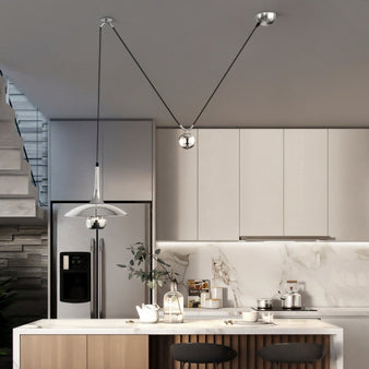 "A single chrome pendant light hangs above a modern kitchen island, providing focused illumination."