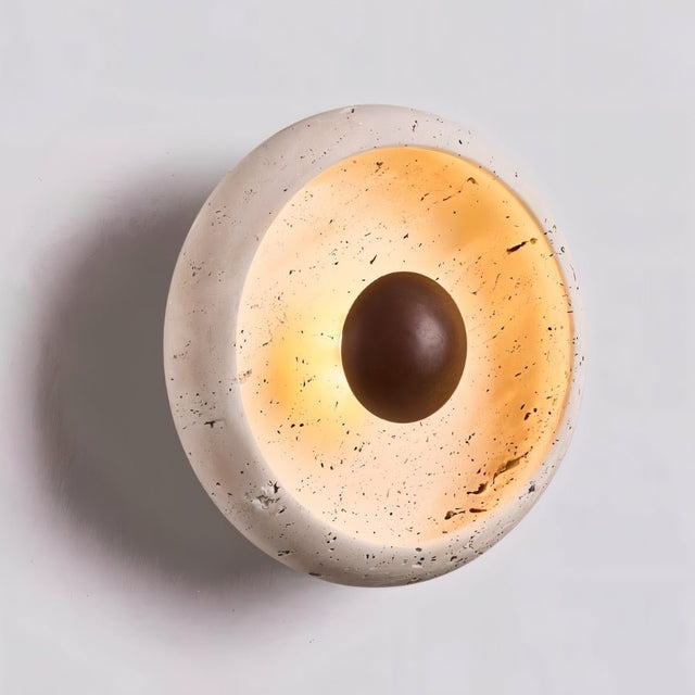"Close-up of a minimalist, circular travertine wall lamp with a warm wooden centerpiece and a soft, ambient glow."
