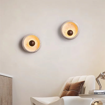 "Circular travertine wall lamps with wooden centerpieces and metal bases, blending organic and modern styles in a living room."