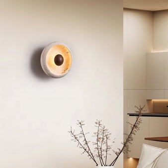 "A modern rustic wall lamp with a circular travertine frame and wooden centerpiece illuminating a contemporary living room."