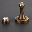"Elegant, sculpted brass door stop with a tapered design and decorative base, shown with its separate magnetic catch component, designed to prevent wall damage in modern and classic interiors."