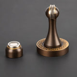 "Elegant, sculpted brass door stop with a tapered design and decorative base, shown with its separate magnetic catch component, designed to prevent wall damage in modern and classic interiors."