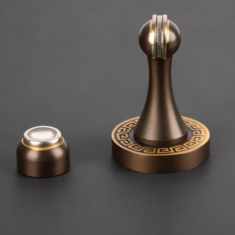 "Elegant, sculpted brass door stop with a tapered design and decorative base, shown with its separate magnetic catch component, designed to prevent wall damage in modern and classic interiors."