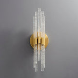 "A gold wall lamp with textured glass rods on a grey wall."