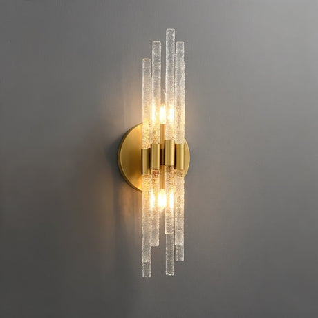 "A modern brass wall light with textured glass rods on a gray wall."