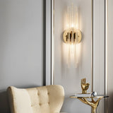 "A modern brass wall sconce with textured glass rods mounted on a panelled wall."