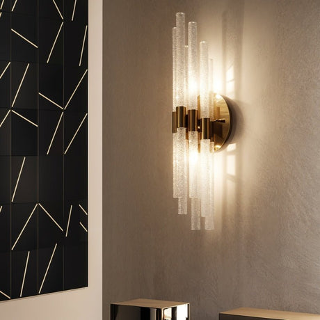 "A modern brass wall lamp with textured glass rods illuminating a living room wall."