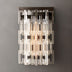 Modern wall sconce with stacked clear and frosted glass rods in brushed nickel finish against gray wall.