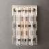 Clear acrylic wall sconce with brushed nickel accents and stacked geometric prisms against a gray background.