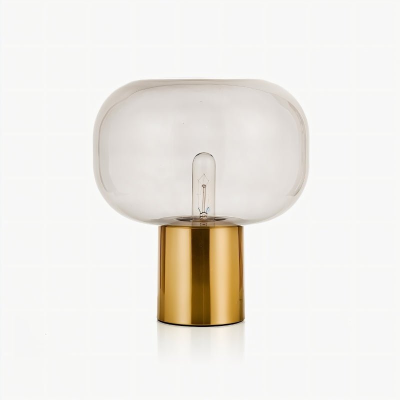 "Zareen table lamp with a clear glass shade and golden aluminum base, designed to enhance any modern space with a soft, diffused glow."