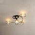 Modern ceiling light fixture with four clear glass shades and brass accents mounted on white ceiling.