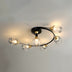 Semi-flush ceiling light with six clear glass globes and brass accents on black curved frame, mounted on white ceiling.