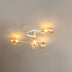 Modern ceiling light with white and brass finish featuring five amber glass shades mounted on cream wall.