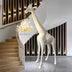 White giraffe-shaped floor lamp with gold chandelier accent in modern stairwell with wooden steps and black slat wall.