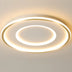 Modern ceiling light fixture with nested oval rings in brushed gold and white acrylic, mounted on cream ceiling.