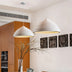 White ridged dome pendant lights hanging above an orange kitchen island with modern cabinetry.