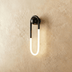 Black and white curved pendant light fixture mounted on beige wall in modern hallway with polished floor.