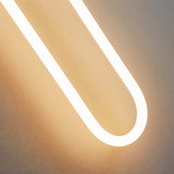  "Close-up detail of the acrylic tubing of a modern, minimalist U-shaped wall lamp, showing the soft, diffused light."