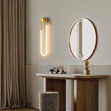 "A modern, minimalist U-shaped wall lamp with a brass finish illuminating a bathroom vanity."