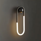 "A modern, minimalist U-shaped black wall lamp emitting a soft, warm light."