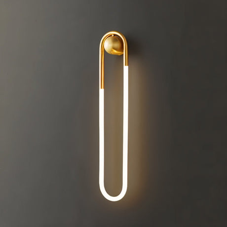 "A modern, minimalist U-shaped wall lamp with a brass finish emitting a soft, warm light."