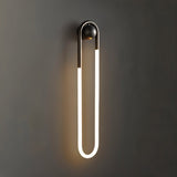 "A modern, minimalist U-shaped wall lamp with a black and brass finish, providing soft illumination."