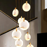 "A multi-tiered alabaster chandelier with brass accents hangs in a modern staircase, creating a luxurious focal point."
