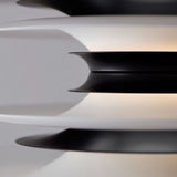"A close-up view of a modern pendant light showing the layered discs in black and white, highlighting the textured design and soft illumination."
