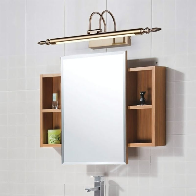 "A silver wall lamp with decorative end caps mounted above a bathroom medicine cabinet with open wooden shelves on either side, against a tiled wall."