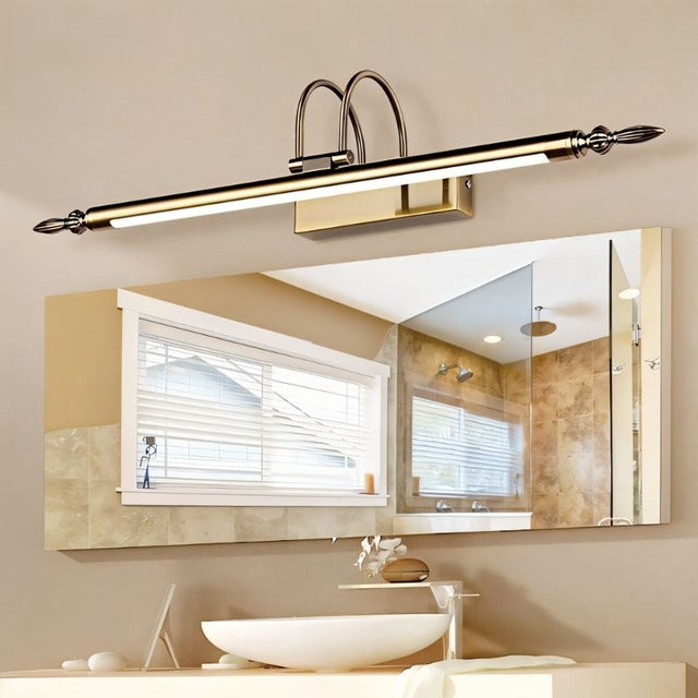 "A silver wall lamp with decorative end caps mounted above a bathroom vanity mirror, reflecting a window and shower, with a modern sink below."