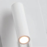 "Close-up of a modern white cylindrical spotlight emitting a focused beam of light, part of a wall-mounted reading lamp."