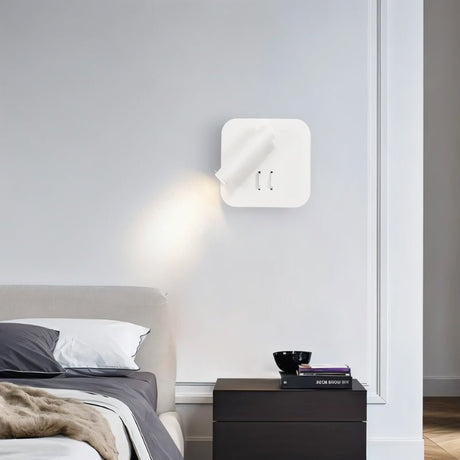 "A modern white wall-mounted reading lamp with a circular backplate and adjustable cylindrical spotlight, in a contemporary bedroom setting."